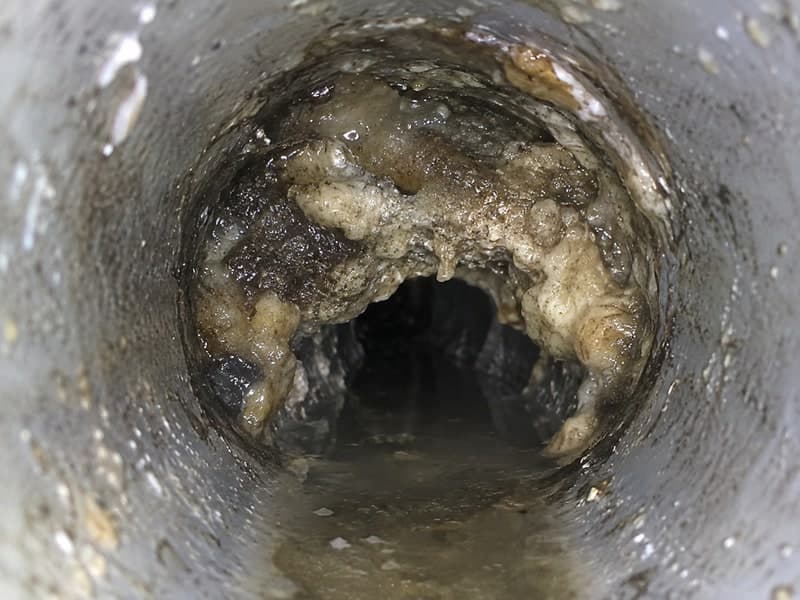 油脂やヘドロが付着して狭くなった清掃前の排水管内部